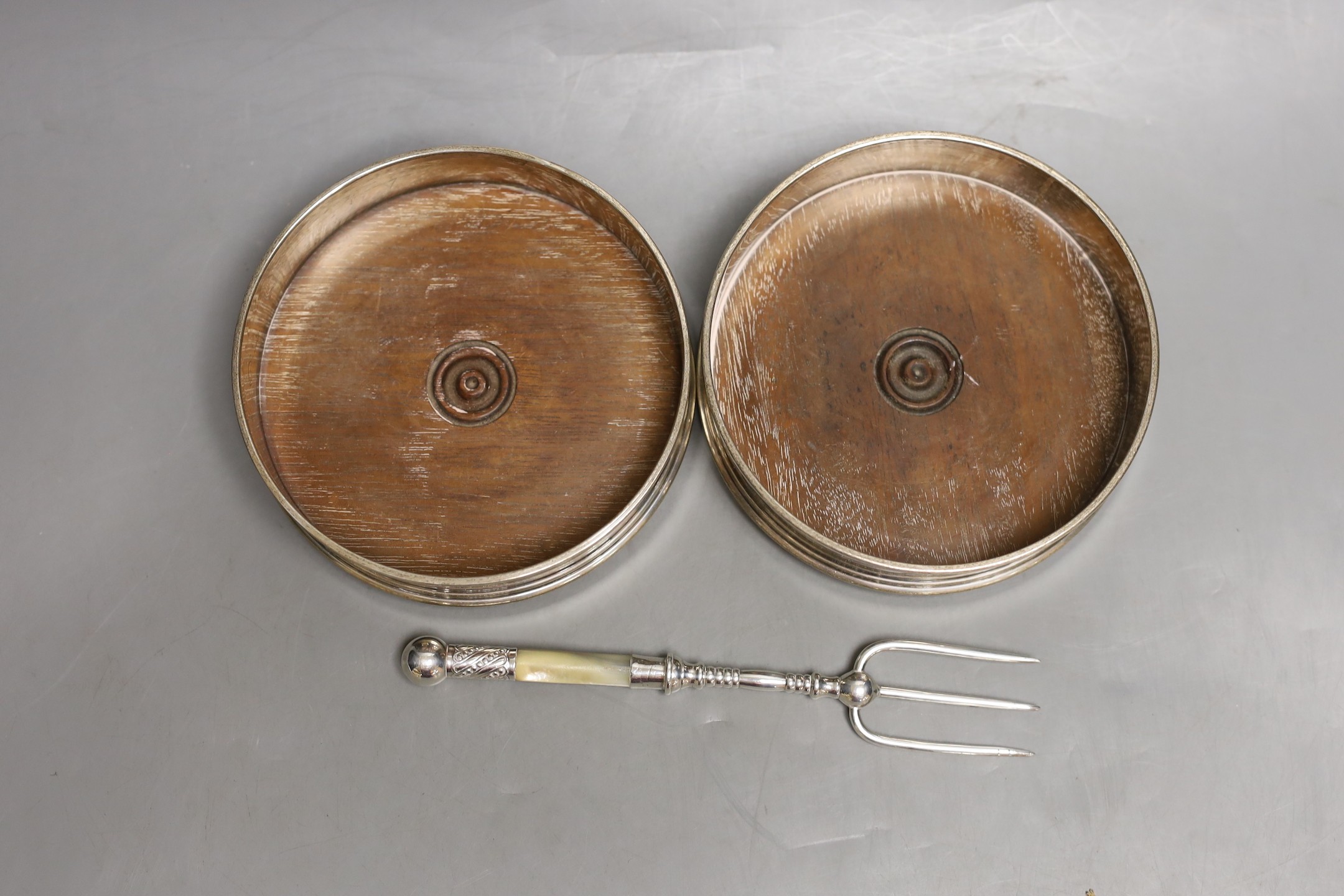 A modern pair of silver mounted wine coasters, London, 1985/6, diameter 12.5cm and a white metal and mother of pearl toasting fork.